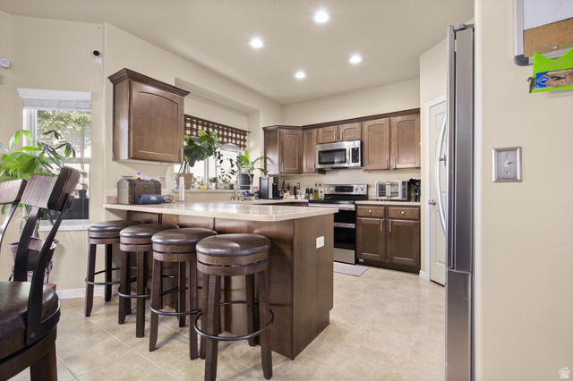 2005 Redtail Way Layton, UT 84040 - Photo 12 of 37 Kitchen featuring a breakfast bar with seating, recessed lighting, wood-finish cabinetry, stainless steel appliances, and light-toned tile flooring