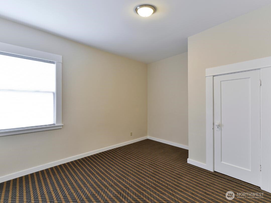 7519 Greenwood Avenue North, Unit 1 Seattle, WA 98103 - Photo 11 of 13 an empty room with wooden floor and windows