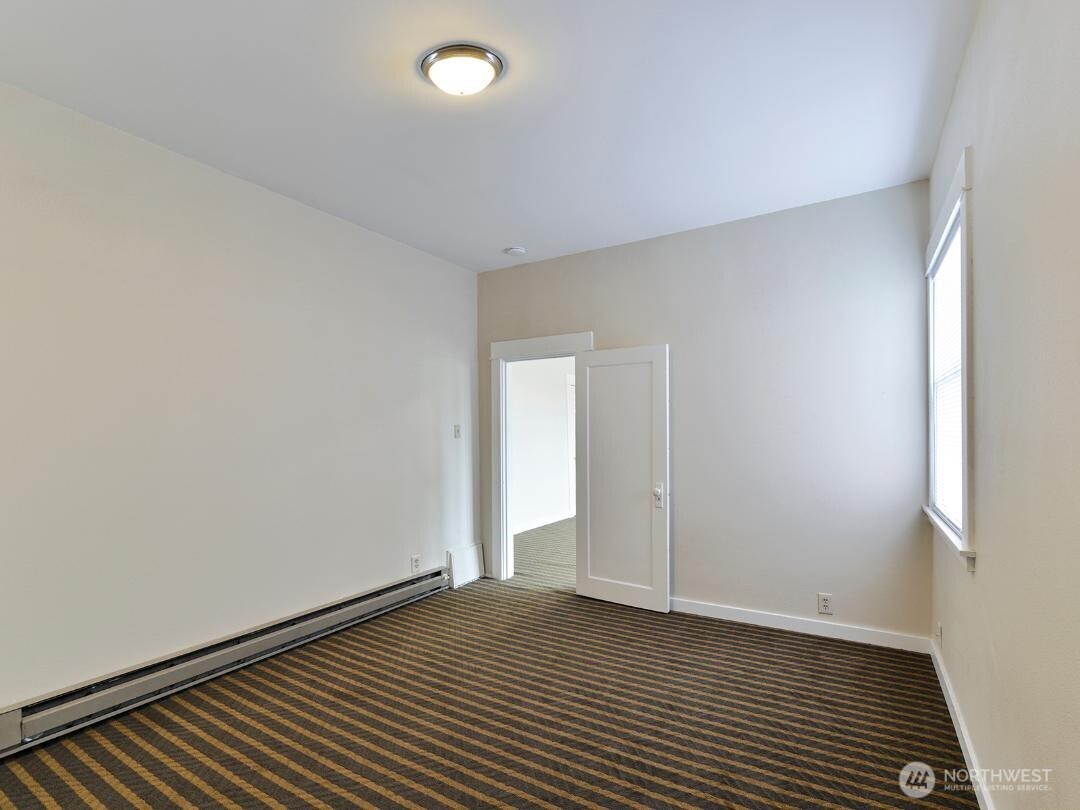 7519 Greenwood Avenue North, Unit 1 Seattle, WA 98103 - Photo 13 of 13 a view of an empty room with wooden floor and a window