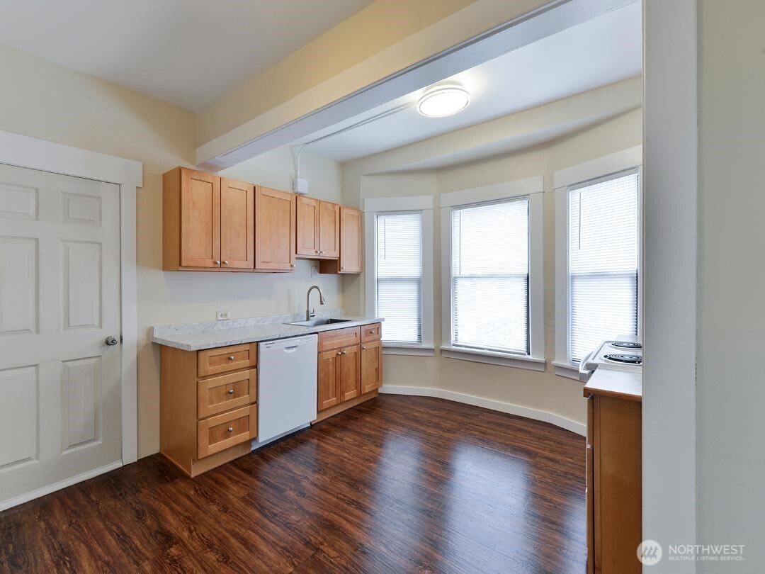 7519 Greenwood Avenue North, Unit 1 Seattle, WA 98103 - Photo 5 of 13 a kitchen with wooden floors and white cabinets