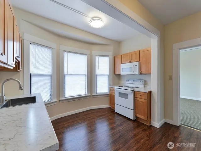 a kitchen with stainless steel appliances granite countertop wooden cabinets a stove a sink and a window