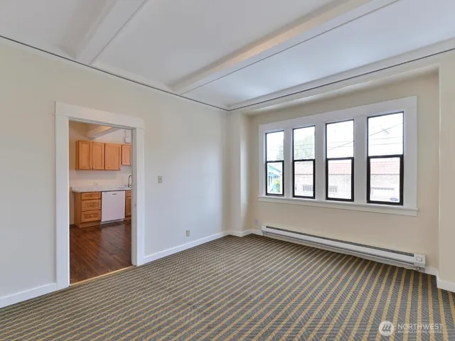 a view of an empty room with a window and wooden floor