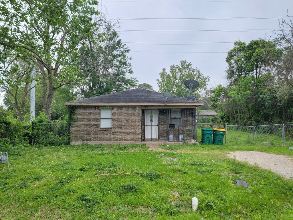 a view of a brick house with a yard and a large tree
