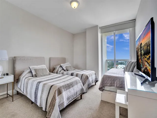 a bedroom with two bed and a flat screen tv