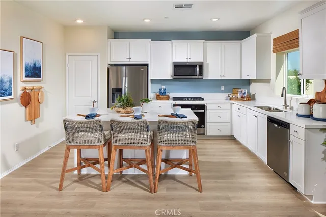 a kitchen with stainless steel appliances kitchen island granite countertop a table chairs microwave and sink
