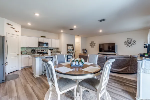 a kitchen with a dining table chairs refrigerator and microwave