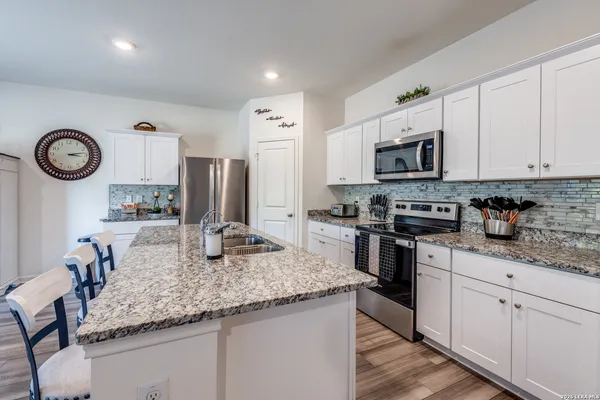 a kitchen with kitchen island granite countertop stainless steel appliances a stove top oven a sink and cabinets