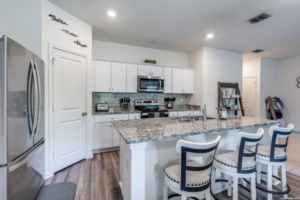 a kitchen with stainless steel appliances granite countertop a stove a sink a microwave a refrigerator and cabinets