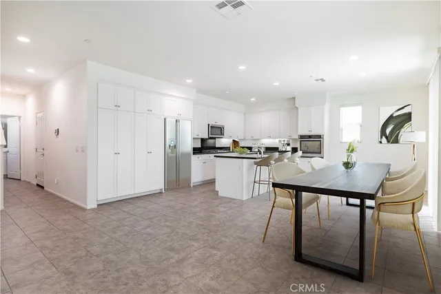 a kitchen with stainless steel appliances granite countertop a table chairs refrigerator and microwave