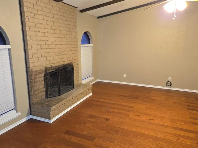 a view of empty room with fireplace and wooden floor