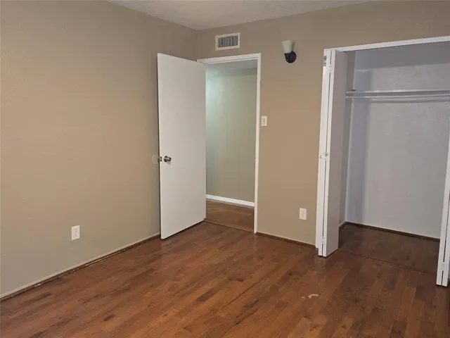 an empty room with wooden floor & closet area
