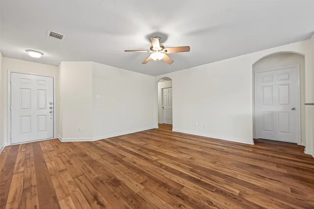 a view of empty room with wooden floor and fan
