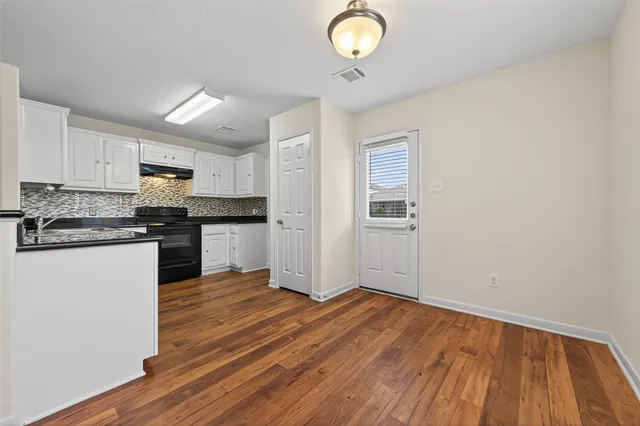 a kitchen with granite countertop wooden floors stainless steel appliances and cabinets