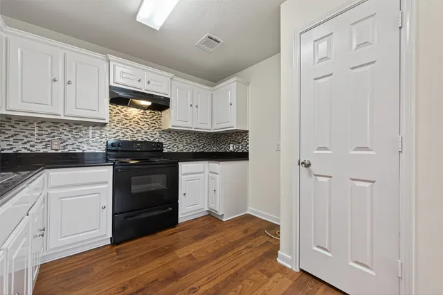 a kitchen with granite countertop white cabinets and black appliances