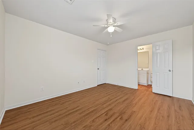 an empty room with wooden floor and fan