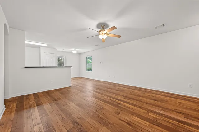a view of a room with wooden floor and a ceiling fan