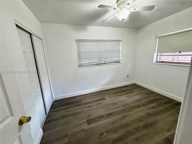 a view of an empty room with wooden floor and a ceiling fan