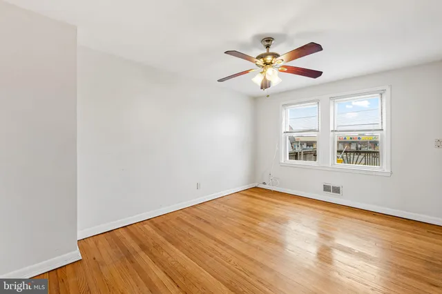 a view of an empty room with window and wooden floor