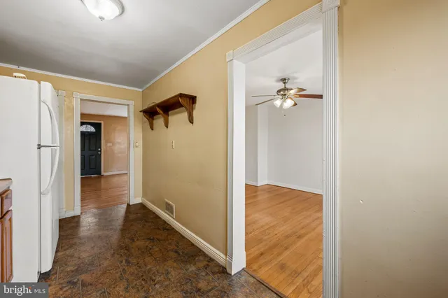 a view of a hallway with wooden floor and a bathroom