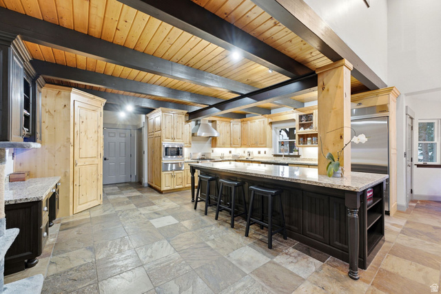 8650 Redden Road Park City, UT 84098 - Photo 8 of 71 Kitchen featuring an expansive island with seating, natural wood cabinetry, stainless steel appliances, exposed wood beams, and a tile floor