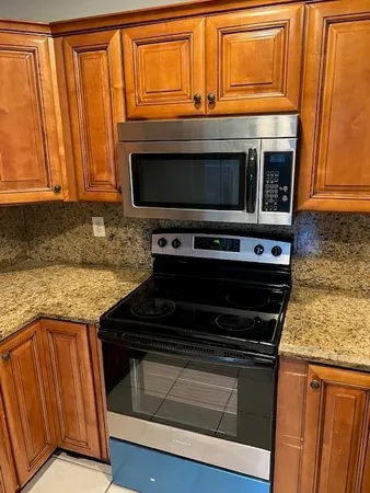 a kitchen with granite countertop cabinets stove and microwave