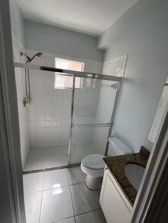 a bathroom with a granite countertop sink toilet and shower