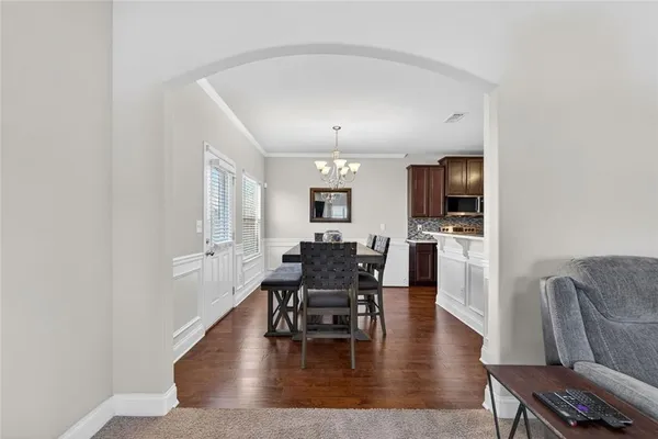 a dining room with wooden floor a chandelier a wooden table and chairs