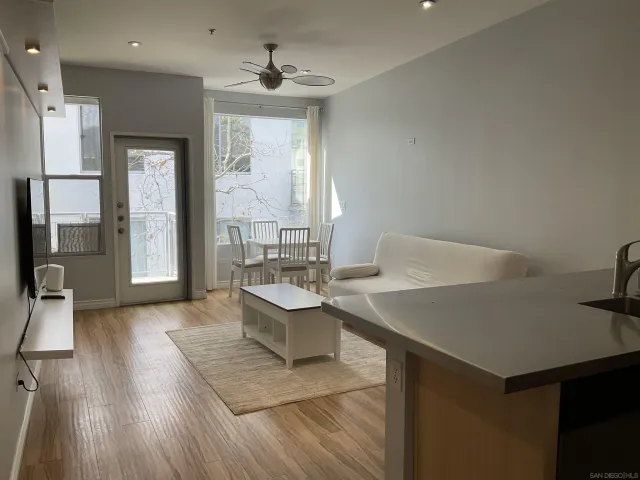 a living room with stainless steel appliances furniture a rug and a kitchen view