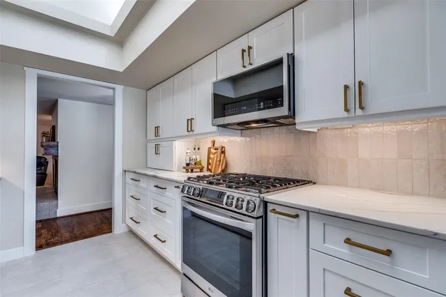 a kitchen with stainless steel appliances white cabinets and a stove top oven