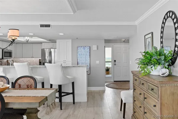 a living room with furniture a potted plant and kitchen view