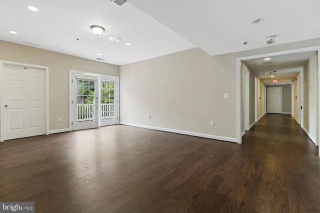 a view of an empty room with wooden floor and windows