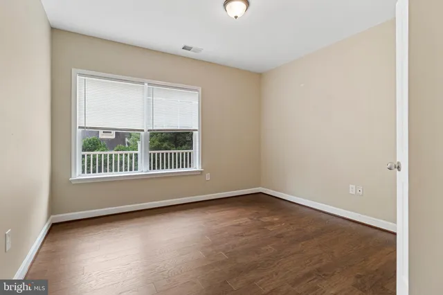 a view of an empty room with wooden floor and windows