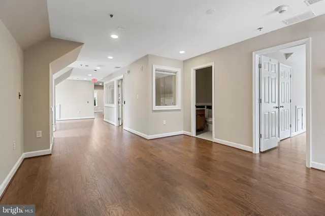 an empty room with wooden floor cabinet and windows