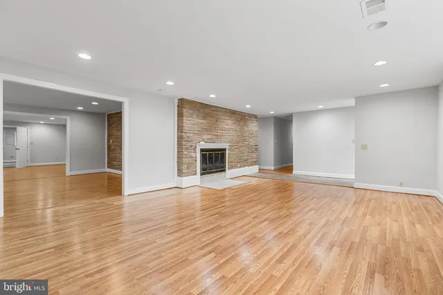 a view of an empty room with wooden floor and a fireplace