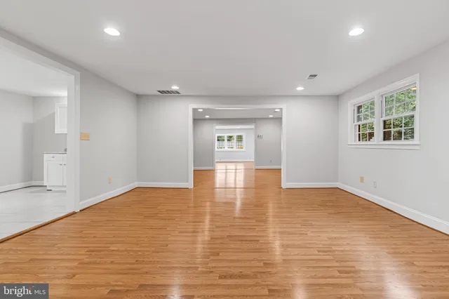 a view of an empty room with window and wooden floor