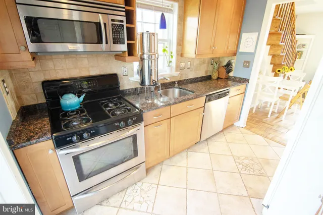 a kitchen with granite countertop a stove a sink and a microwave