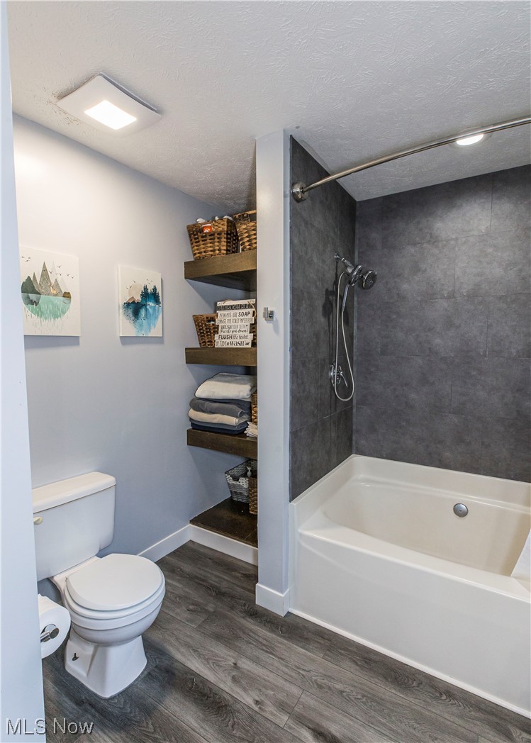 1804 Grace Road Akron, OH 44312 - Photo 8 of 15 Bathroom featuring a textured ceiling, tiled shower / bath combo, and hardwood flooring