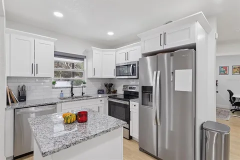 a kitchen with stainless steel appliances granite countertop a refrigerator stove and sink
