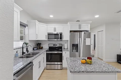 a kitchen with stainless steel appliances granite countertop a sink stove and refrigerator