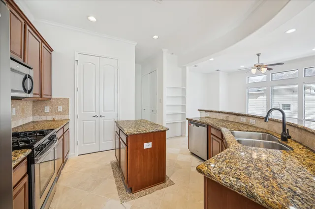 a kitchen with stainless steel appliances granite countertop a stove top oven a sink dishwasher and a refrigerator with wooden cabinets