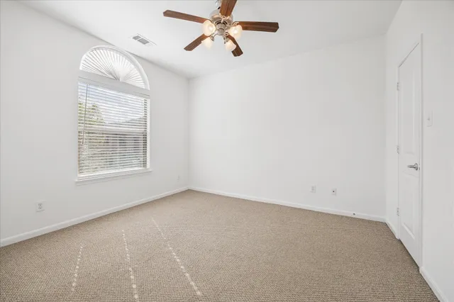 a view of a big room with windows and chandelier fan