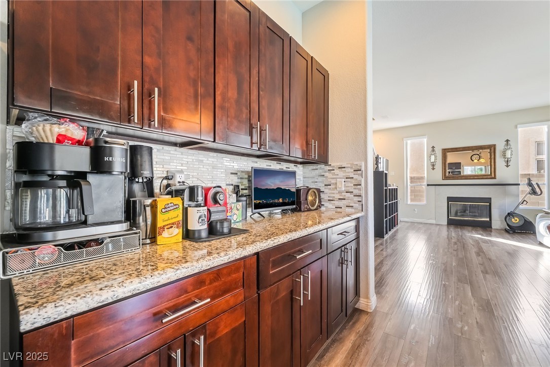 1081 Deep Well Court Henderson, NV 89011 - Photo 14 of 44 Kitchen featuring light stone countertops, tasteful backsplash, dark wood-type flooring, and reddish brown cabinets