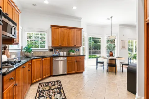 a kitchen with stainless steel appliances a stove a sink a counter top space and living room filled with furniture