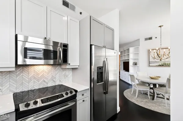 a kitchen with stainless steel appliances white cabinets and a stove top oven