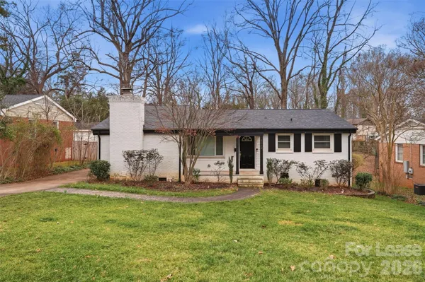 a front view of a house with a garden and trees