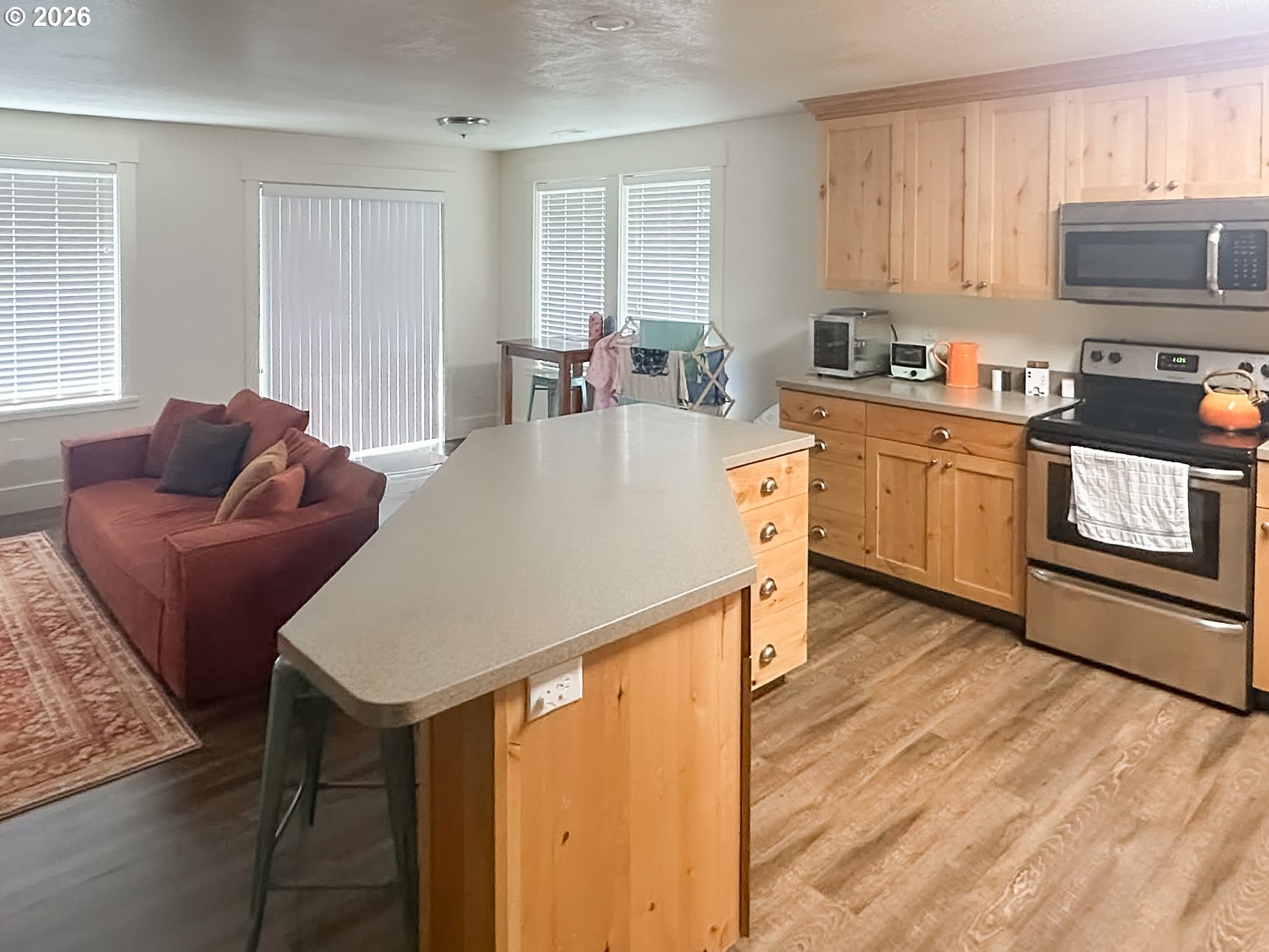 1601 Spruce Drive Seaside, OR 97138 - Photo 4 of 7 a living room with stainless steel appliances furniture a kitchen island wooden floors and a window