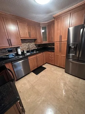 a kitchen with stainless steel appliances granite countertop a stove top oven a sink dishwasher and a microwave