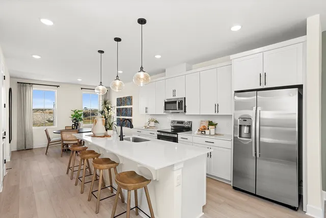 a kitchen with stainless steel appliances a refrigerator a stove a sink a dining table and chairs