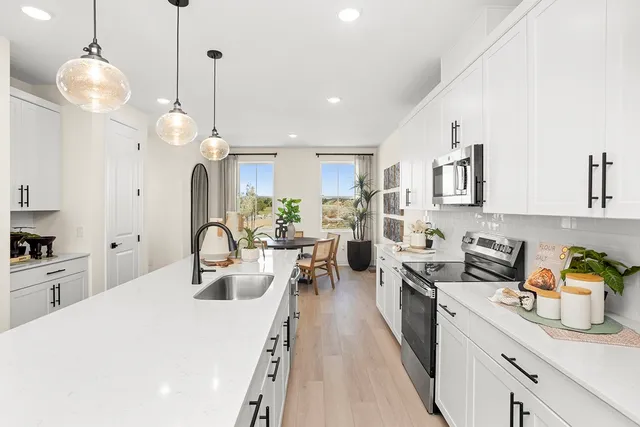 a kitchen with stainless steel appliances a stove a sink a refrigerator a center island a dining table and chairs