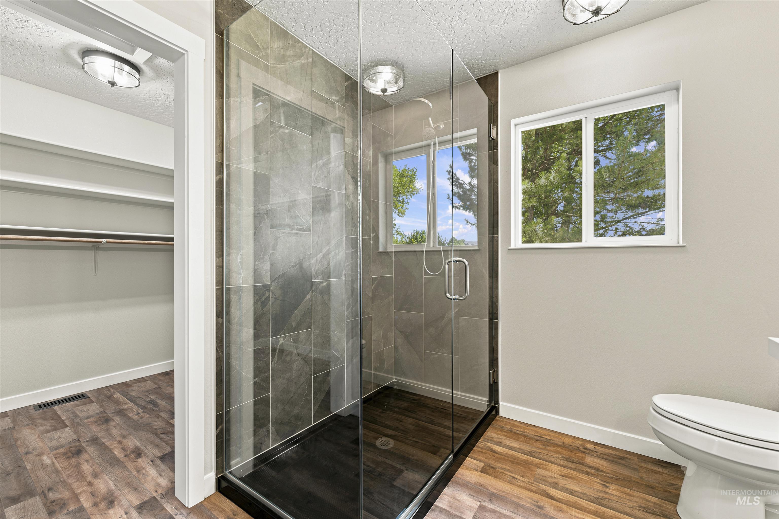 24864 Coventry Drive Caldwell, ID 83607 - Photo 27 of 49 Glass-enclosed shower with dark tile surround, featuring a window and recessed lighting